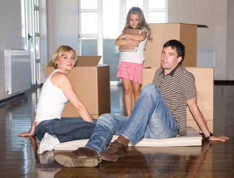 Professional movers carrying furniture through a narrow hallway in Queens Park